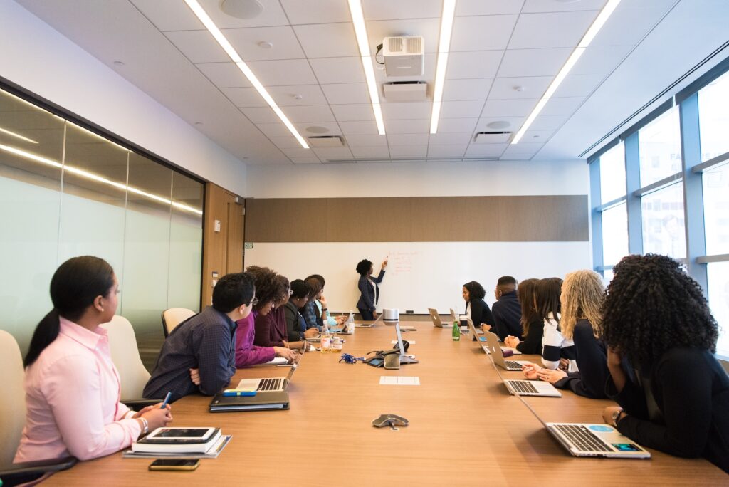 Habilidades Interpessoais em Destaque: Pessoas na mesa de conferência, com atenção voltada para a mulher falante.